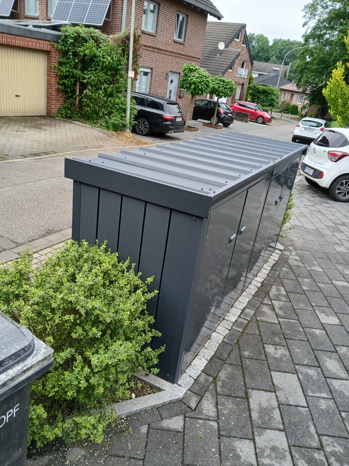 Mülltonnenbox aus Metall mit Lamellentür und Wellblechdach